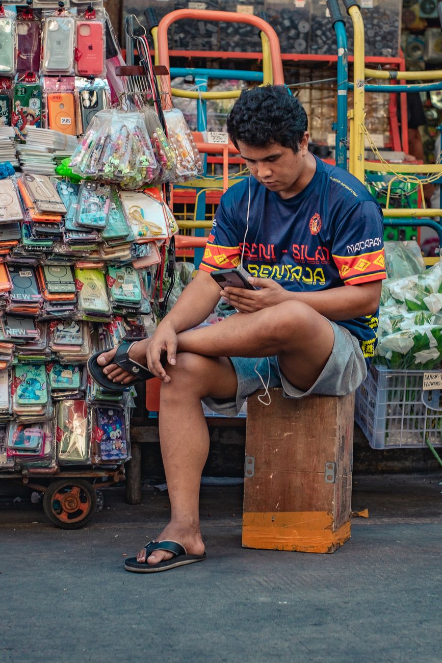 street vendor browsing smartphone in manila