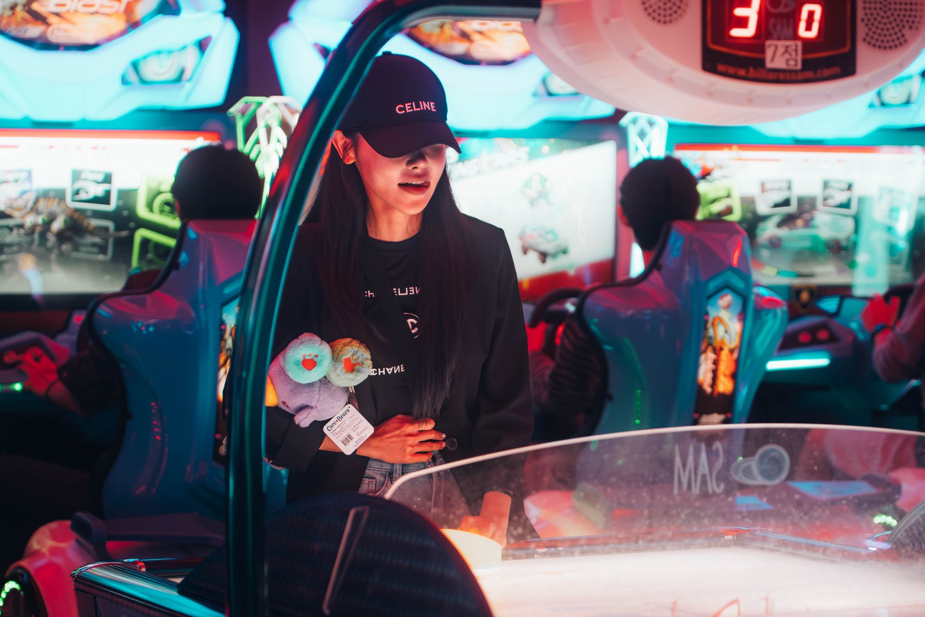 a woman in a black hat and jacket at a video game arcade